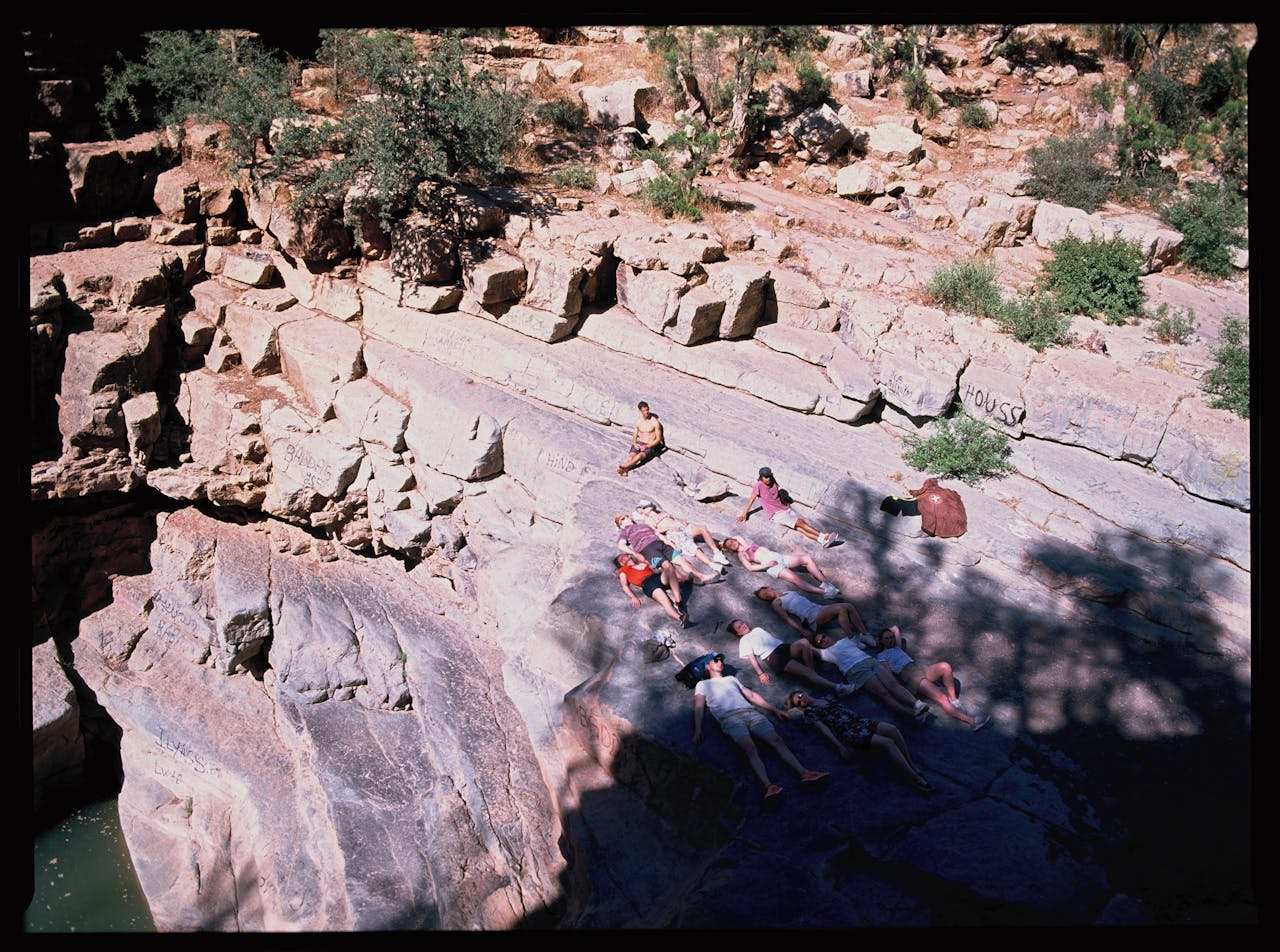 Crafting Captivating Headlines: Your awesome post title goes here Group of people lounging on rocks under the Moroccan sun, captured from above.
