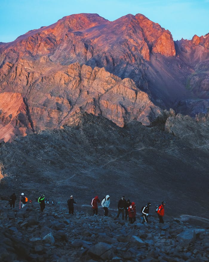 creative-03 A group of hikers walking through rocky terrain in the scenic Al-Aroui mountains at dusk.