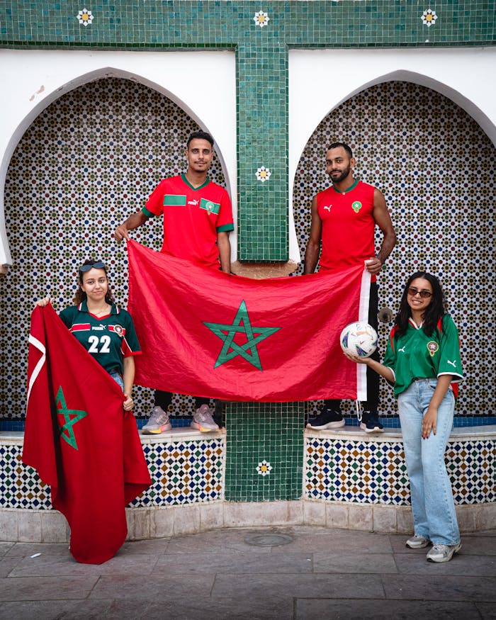 mobile-01 Four Moroccan football fans holding their national flag pose proudly.