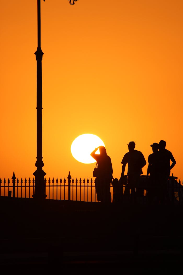 creative-02 Silhouetted figures against a vibrant orange sunset in Morocco.